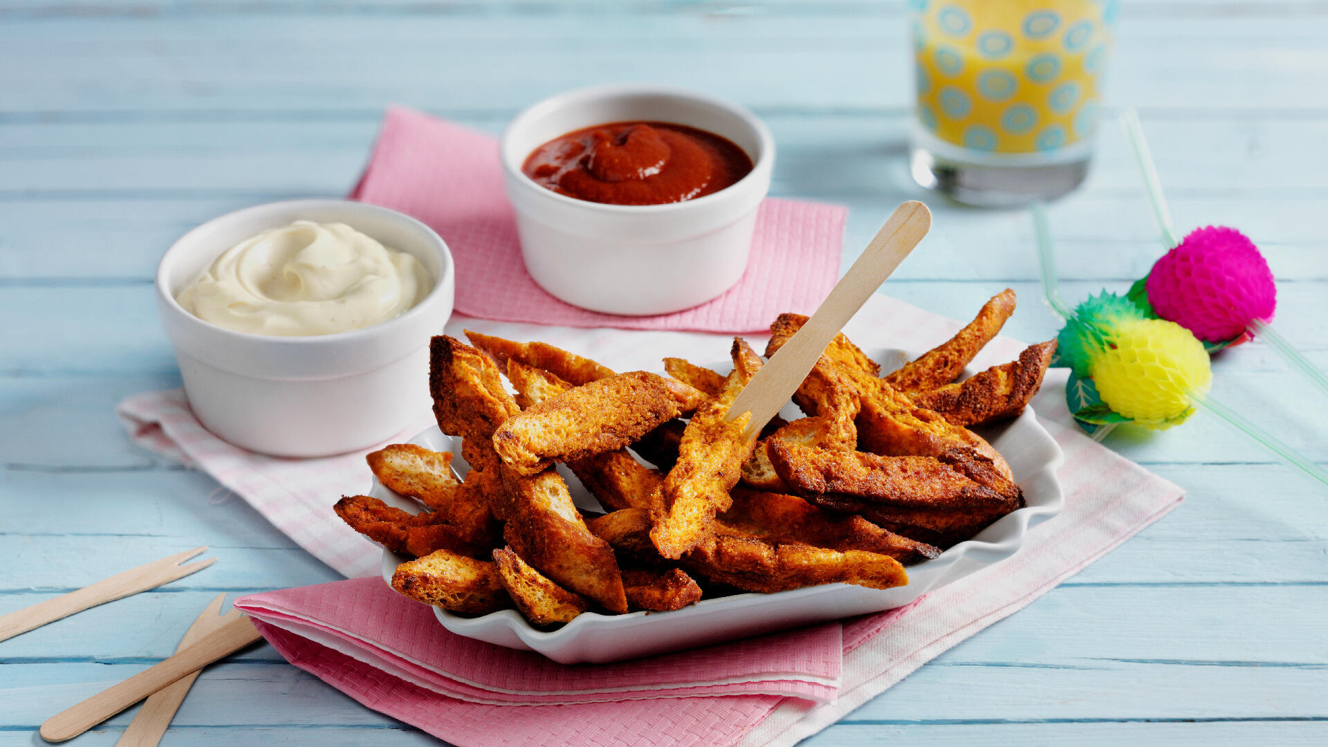 Rezeptfoto: Neben einer Schachtel mit Pommes aus Brot stehen zwei Schälchen mit Mayo und Ketchup
