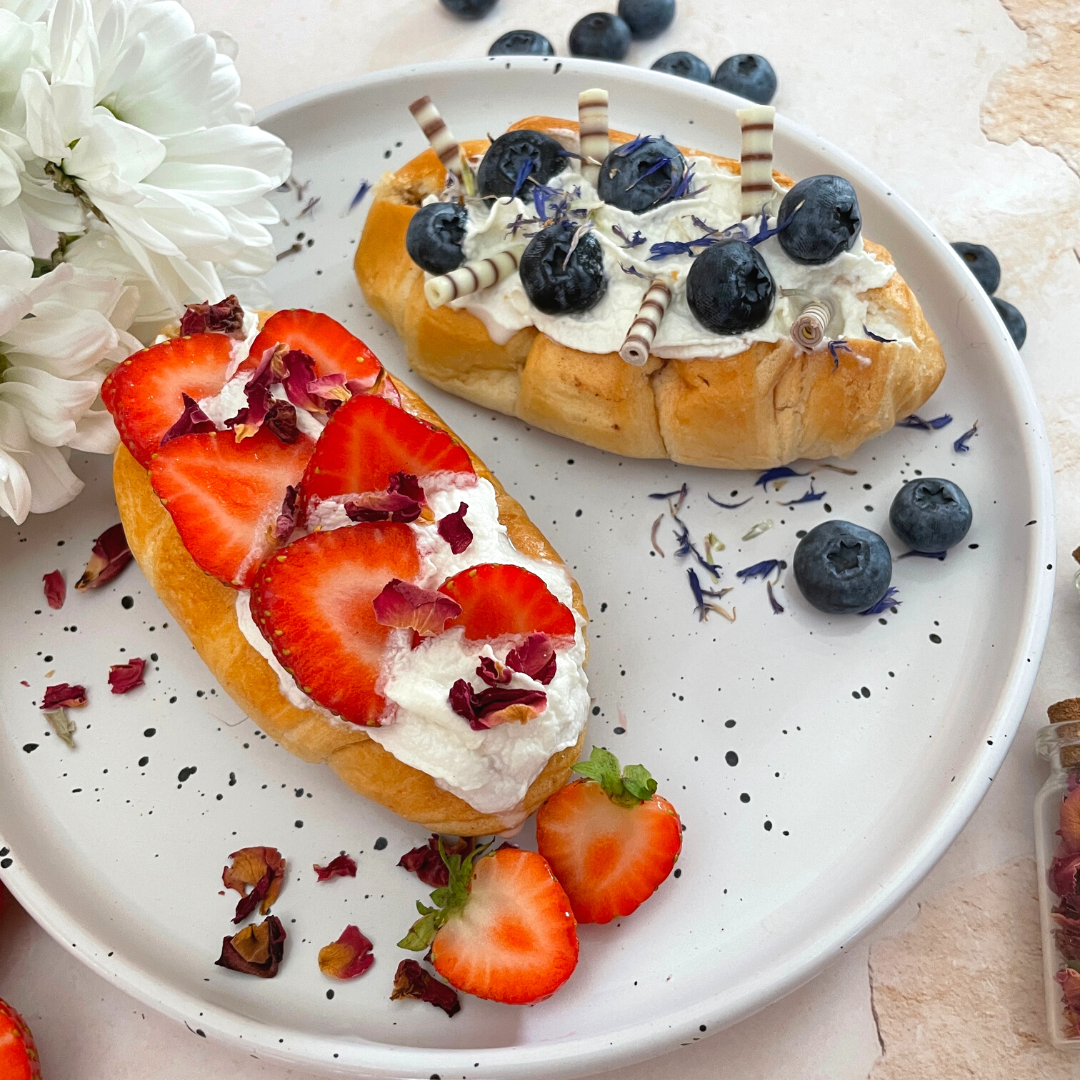 Teller mit Milchbrötchen und Sahne und Obst