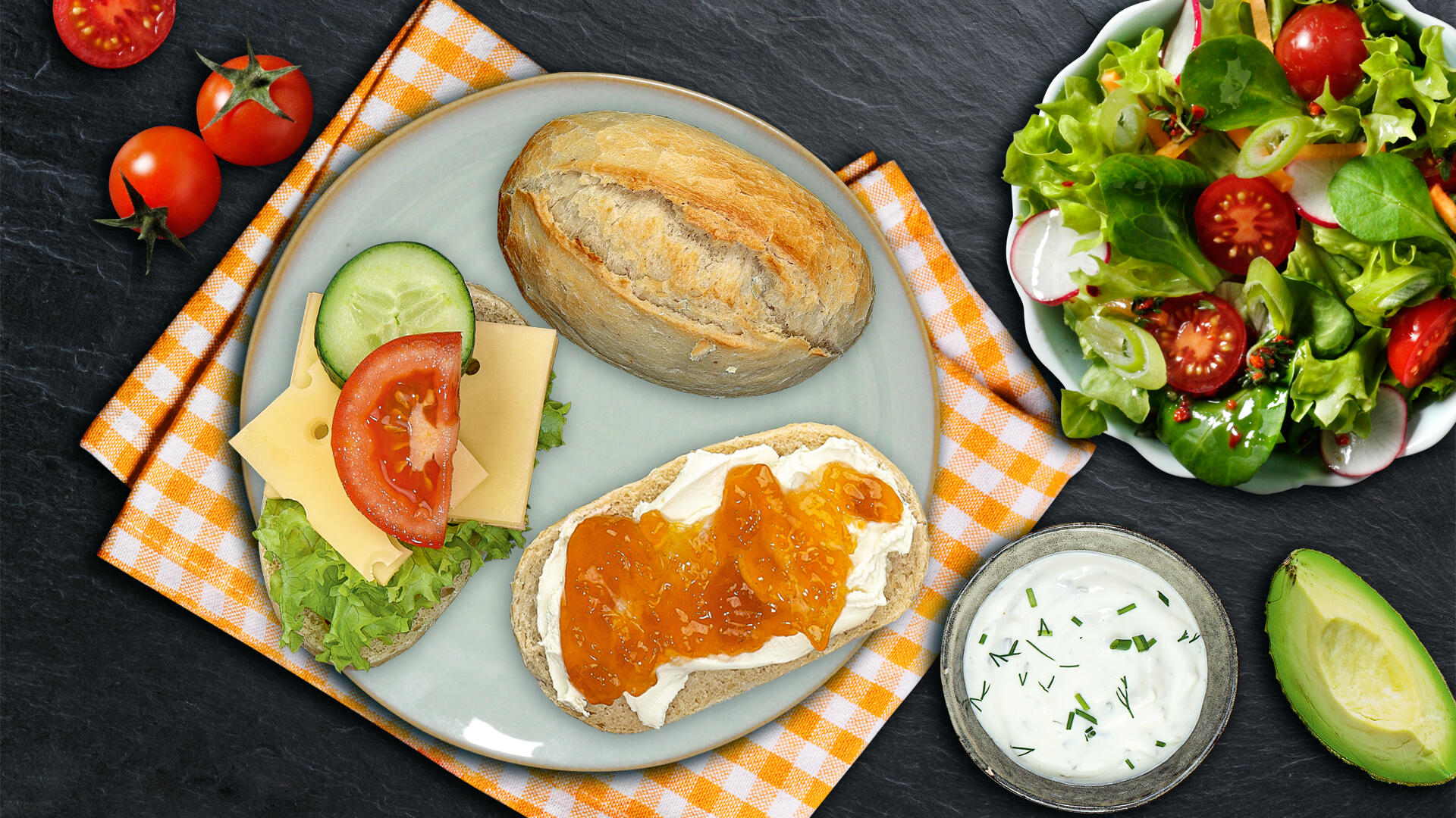 Baguette Brötchen mit Froschkäse und Marmelade und ein Baguette Brötchen mit Käse, Salat, Gurke und Tomate auf einem Teller