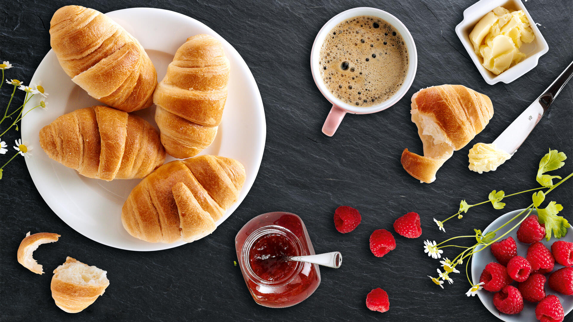 Mini Croissants auf einem Teller mit Marmelade, Kaffee und Butter.